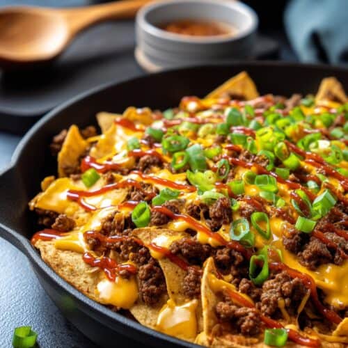 a cast iron pan of nachos with groune beef and cheese sauce
